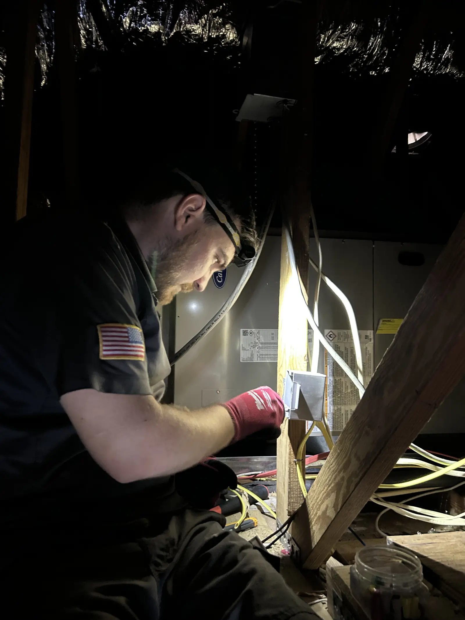Kincaid Electric electrician at work Kincaid Electric electrician with a headlamp wiring a circuit in a dark attic